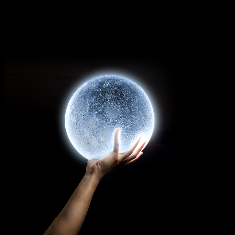 Close up of human hand holding blue glowing moon